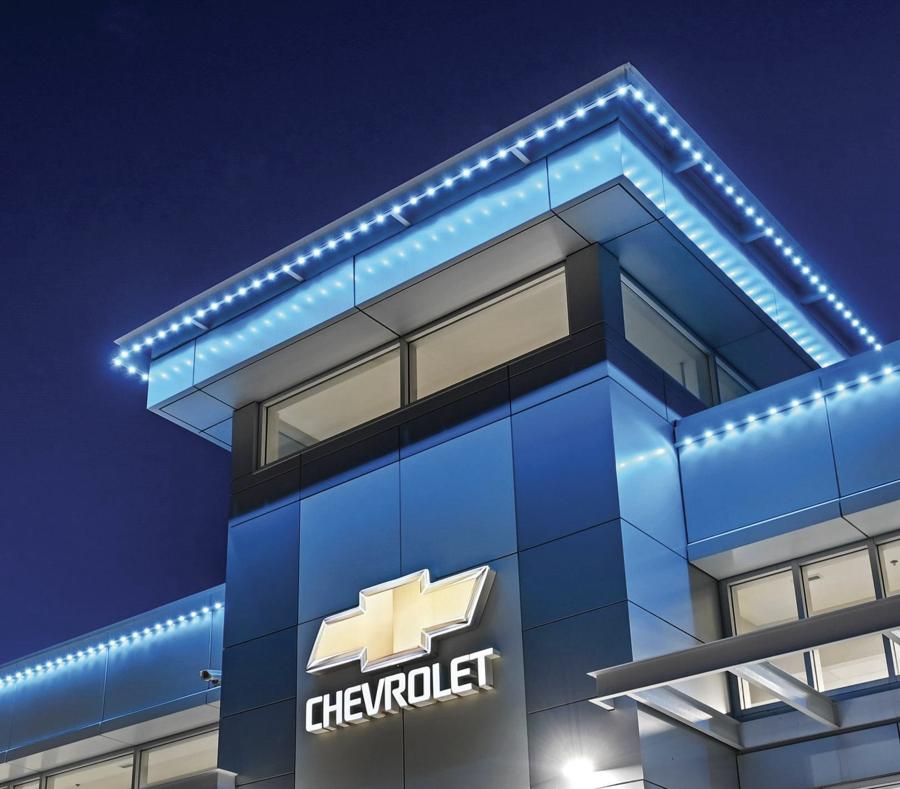 A commercial building lit in blue along its roofline