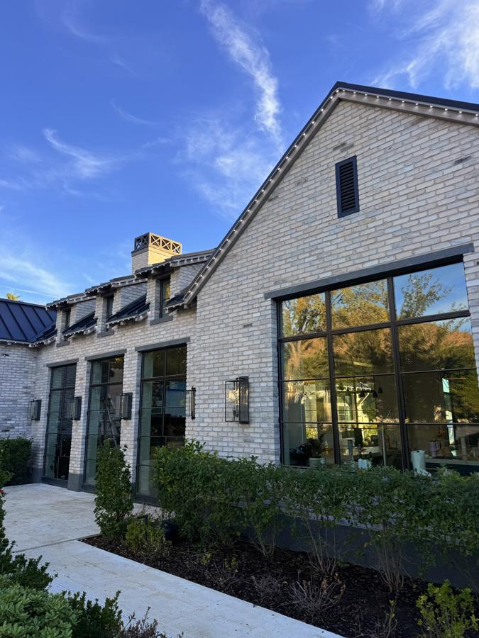 A brick home in daylight where the lighting track is hard to see along the roofline