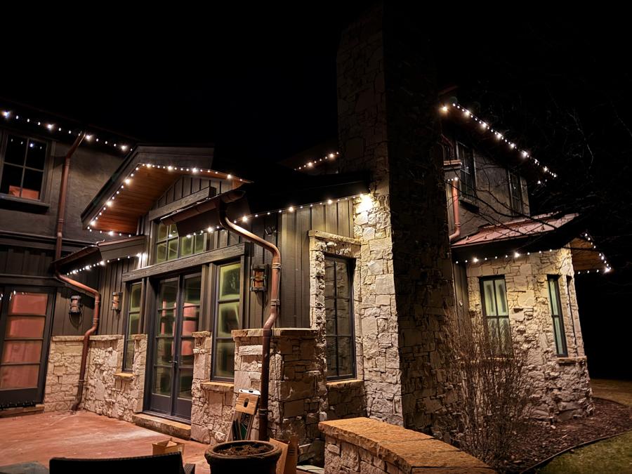 A stone and timber home with lights following each roofline and gable